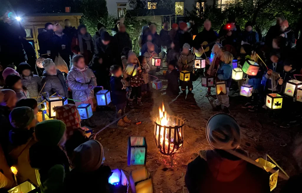 Kinder und Eltern stehen um einen Feuerkorb und singen Lieder beim Lichterfest der Grundschule an der Lessingstrasse Bremen